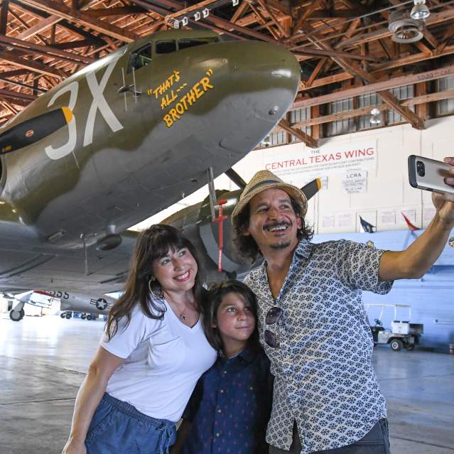 A family takes a selfie in front of a restored WWII-era Douglas C-47 Skytrain in San Marcos, TX