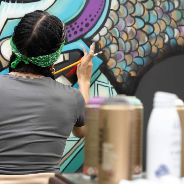 An artist finesses a large mural painting during the San Marcos Studio Tour