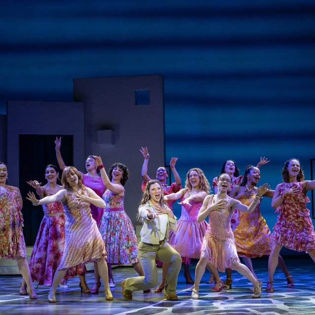 Dancers on the stage in bright patterns and dresses.