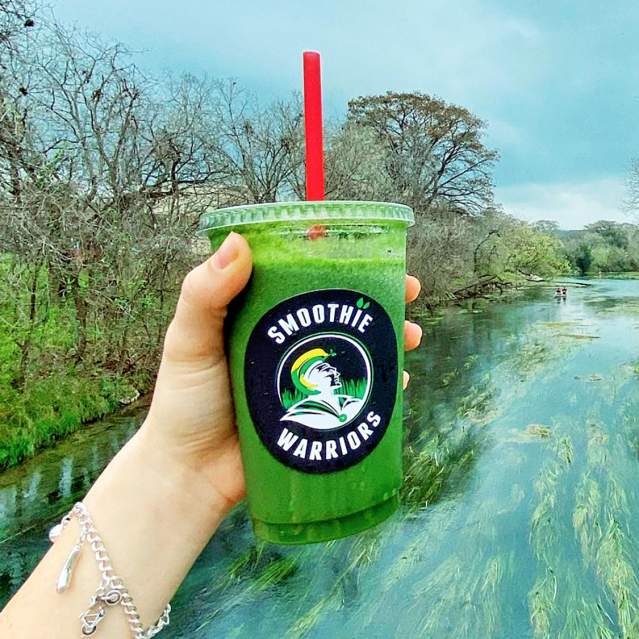 Green smoothie in hand with river in background