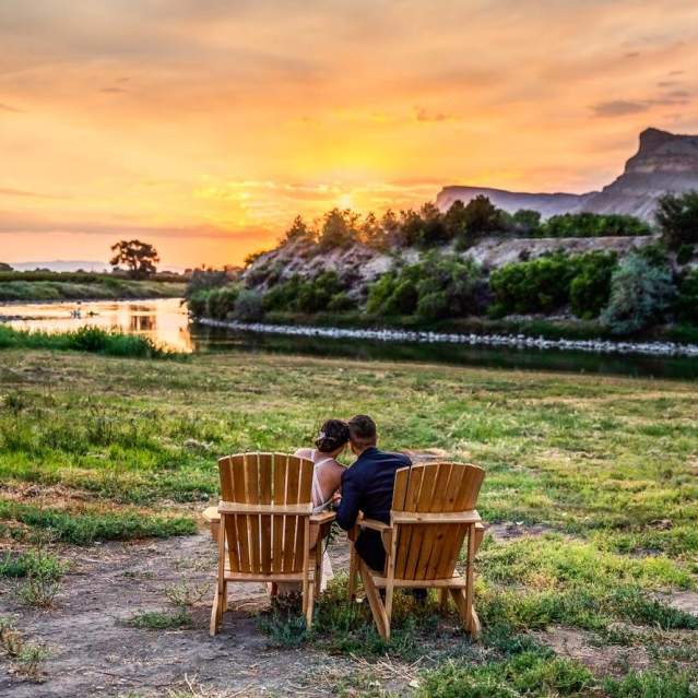 Married couple sits and watches the sunset on the banks of the Colorado River