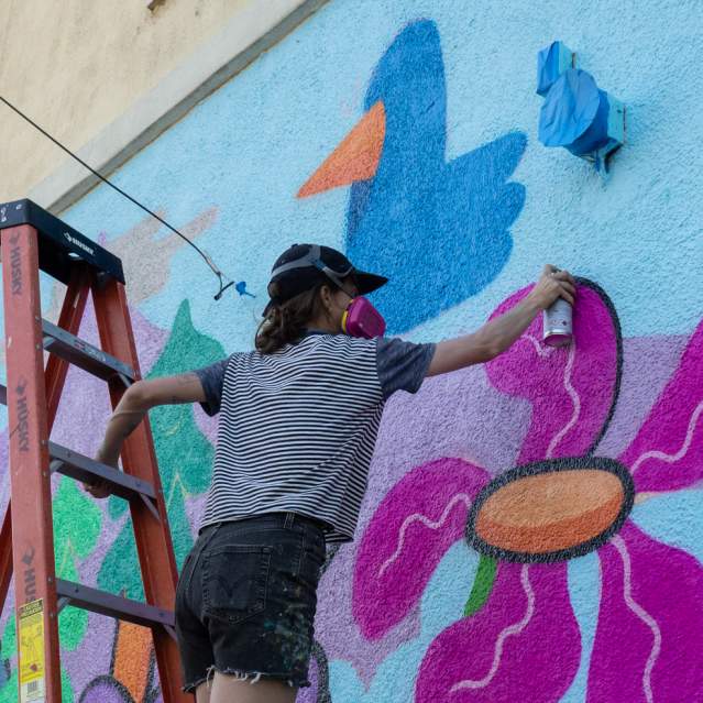 Hannah Eddy on ladder with spraypaint.