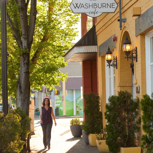 A woman in warm weather walking down Main Street in Springfield by the yellow Washburne Cafe.