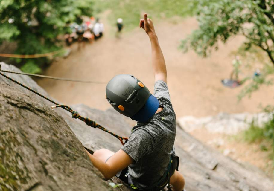 Man rock climbing on a cliff giving a thumbs up