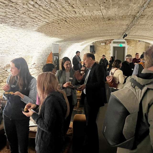 Groups of people stand talking in the Vaulted Cellar at Kings Head Hotel in Cirencester