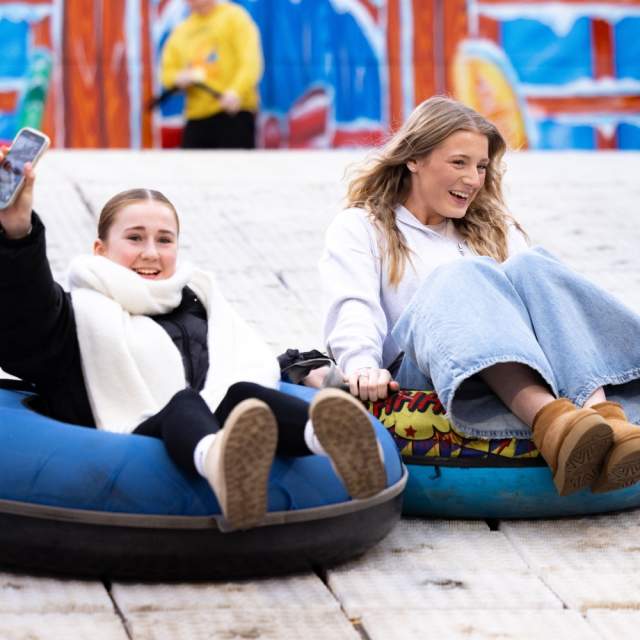 Two girls sliding down the big snow slide at the Christmas Market