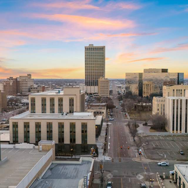 A sunset view over downtown Amarillo, with city streets leading toward tall office buildings and the sky glowing in shades of pink, orange, and blue. The skyline reflects the charm and energy of the Texas Panhandle’s largest city.