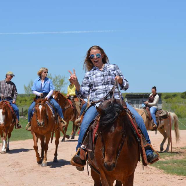 woman doing peace sign on horseback