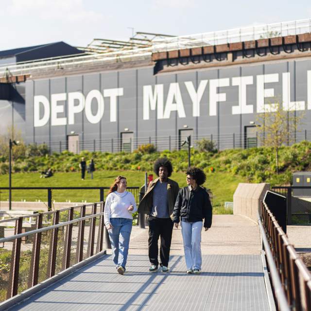 Friends walking along a bridge at Mayfield Park with Depot Mayfield sign in the background