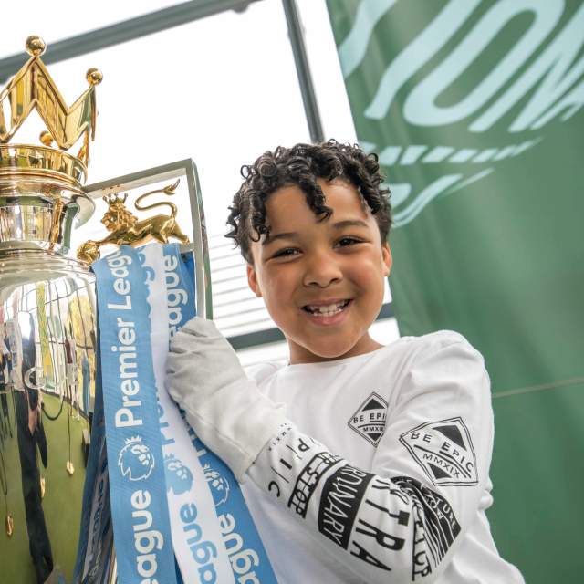 Young person holding up premier league trophy at National Football Museum in Manchester