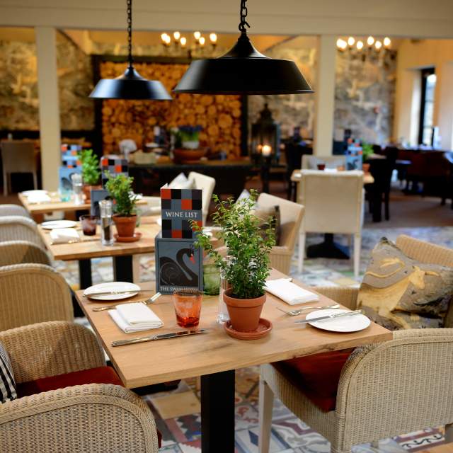 Comfortable whicker dining chairs, a patchwork tiled floor and statement lighting create an eclectic dining space at The Swan Hotel