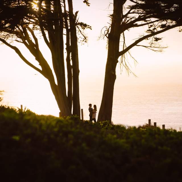 Couple taking engagement photos overlooking the Pacific Ocean