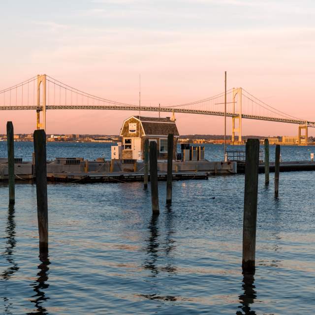 a small building on a pier with a bridge in the background