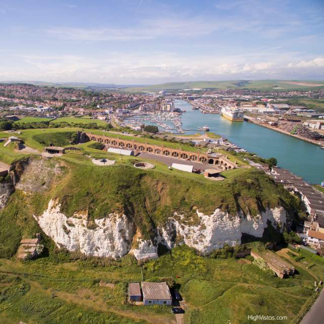 Aerial view of the grounds and red brick buildings of Newhaven Fort with sea in the distance
