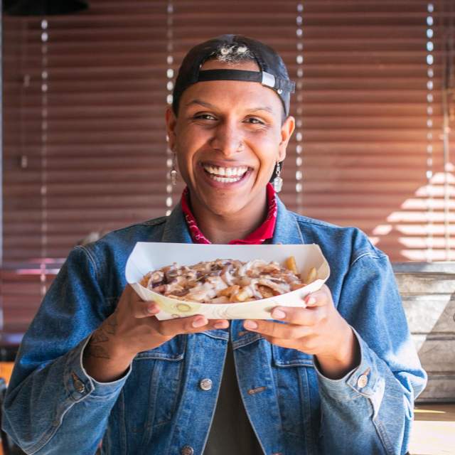 Man smiling holding fries from yellow city street food