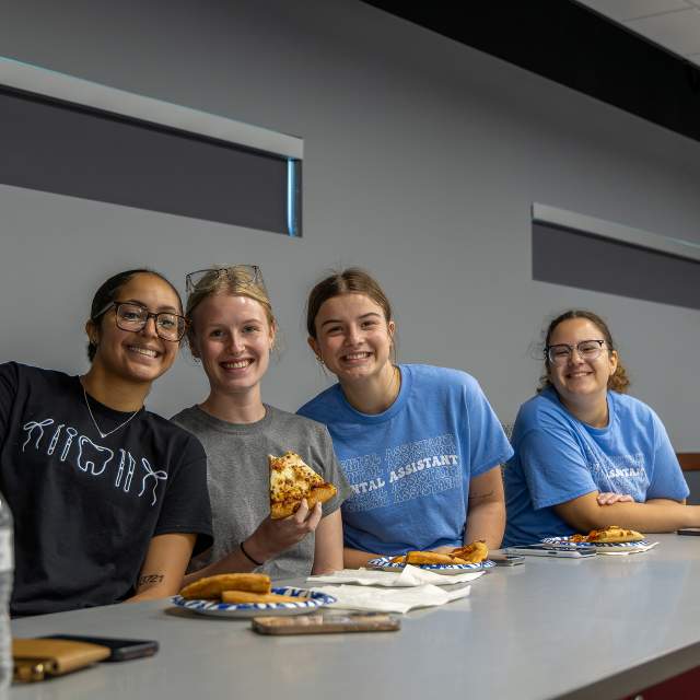 A group of 4 students eating pizza at Salina Tech in Salina, Kansas