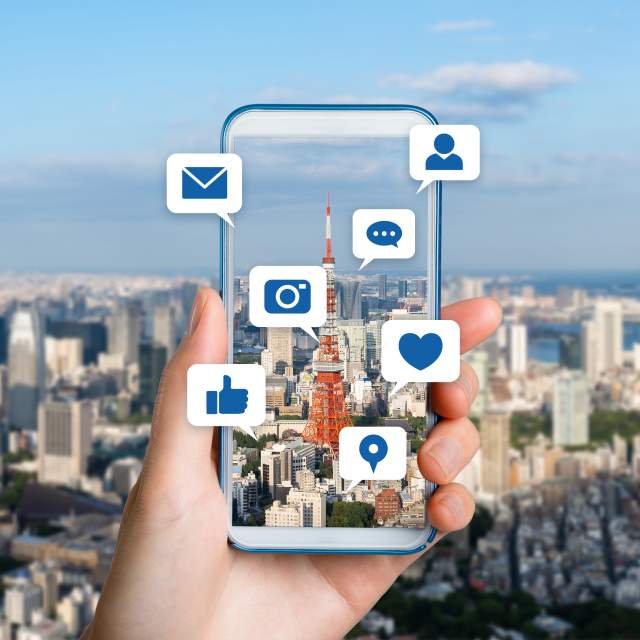 mobile phone with symbols from social media platforms with city in background