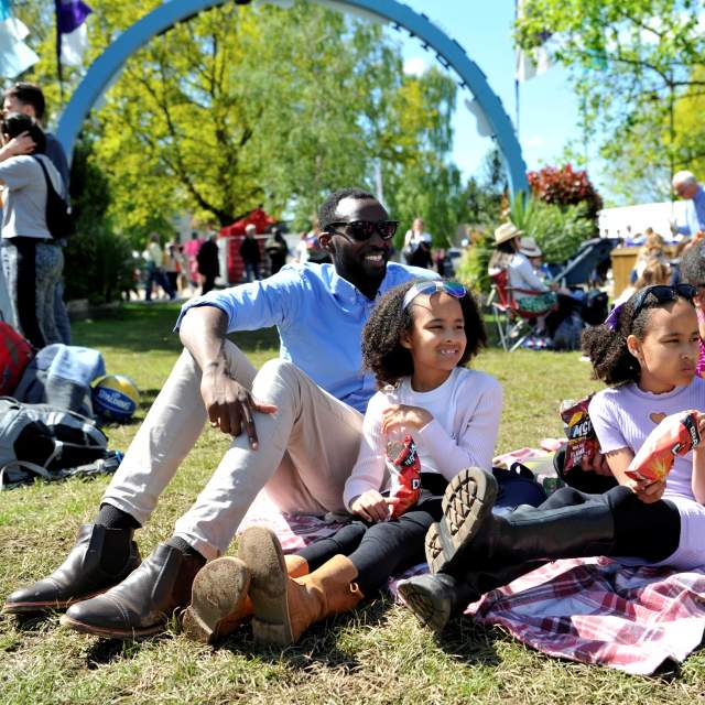 Family sitting in the grass at the Cheltenham Jazz Festival, Imperial Gardens.