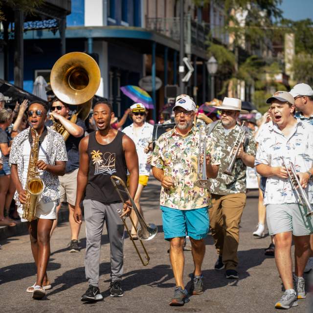 A group of musicians walking down Dauphin Street in downtown Mobile.