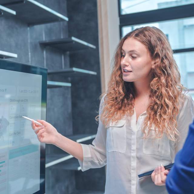 A woman with curly hair stands at a chart