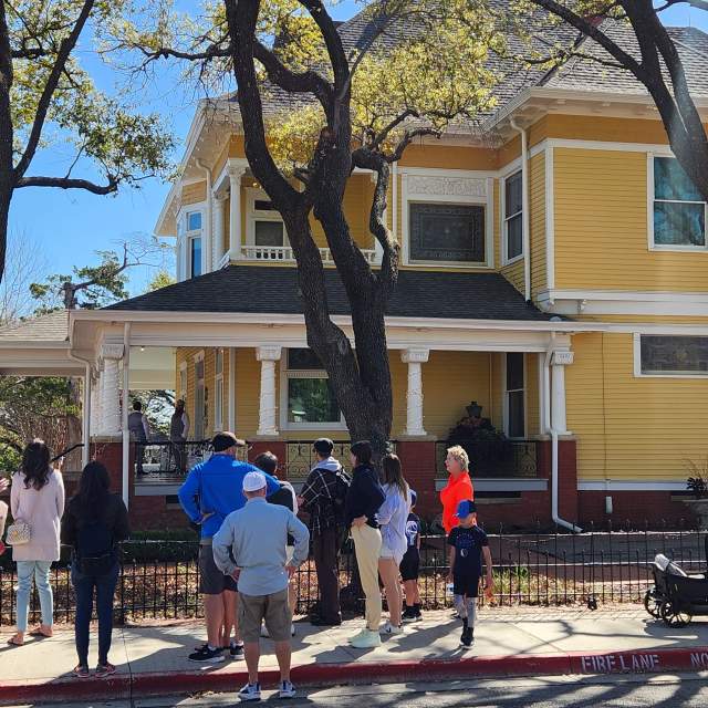 Historic district walking tour - people staying in front of a big old yellow home