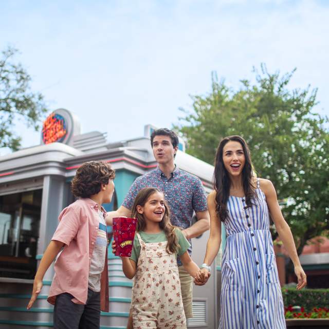A family walking and sharing popcorn in a theme park.