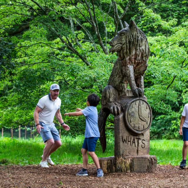 Family playing around wooden statue at Westonbirt Arboretum