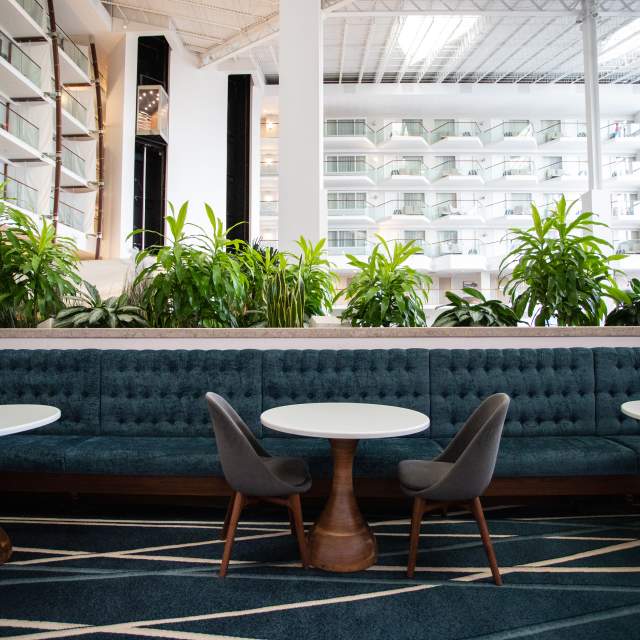 A lobby lounge with a blue couch, white tables, and gray chairs.