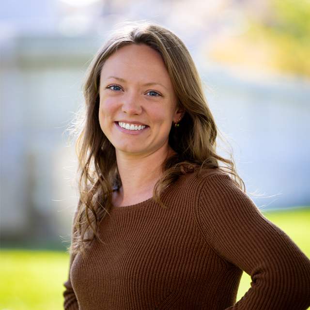 A white woman in a brown sweater standing outside in front of the Wisconsin State Capitol building.