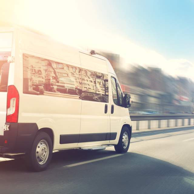 White passenger van on road with blurred background