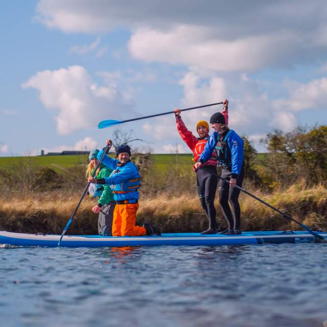 A group of paddleboarders sit and stand on their board in the river in the South Downs National Park