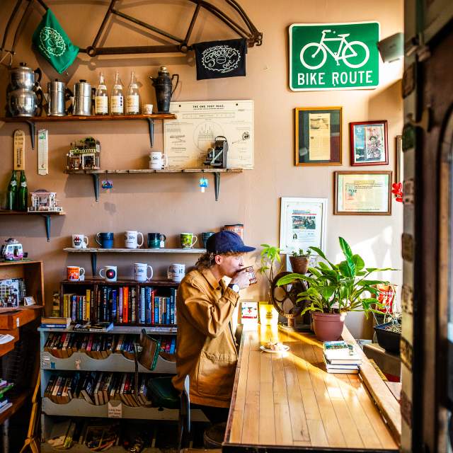 side view of a person sitting at a window drinking a cup of coffee at Sprocket Cafe