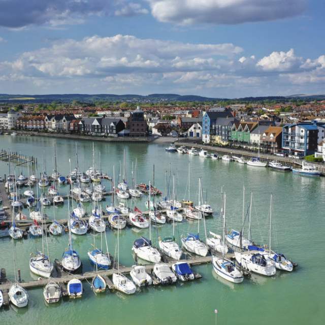 Yachts moored on the river at Littlehampton harbour, with riverside apartments on the opposite side