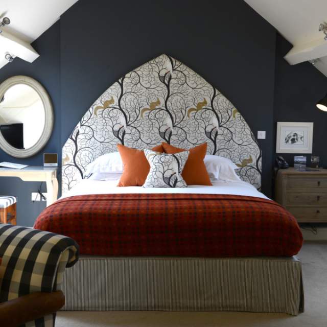 Bedroom at The Close Hotel in Tetbury with dark blue wall and elaborate headboard