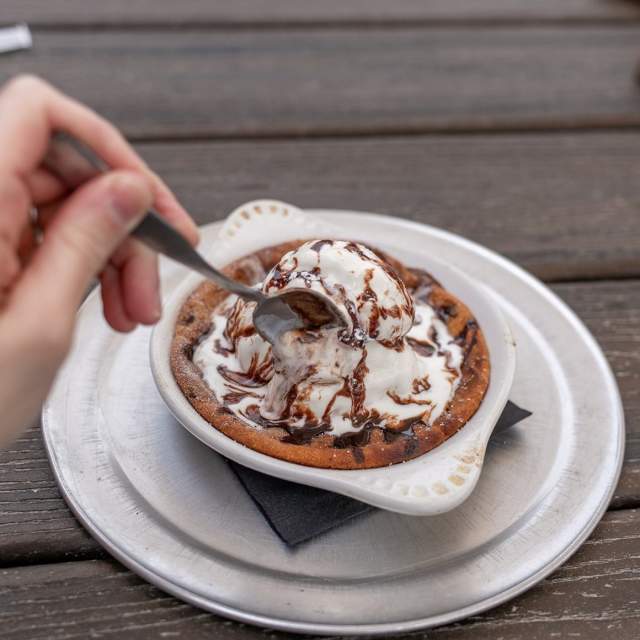 An individual chocolate chip pie with ice cream and chocolate syrup