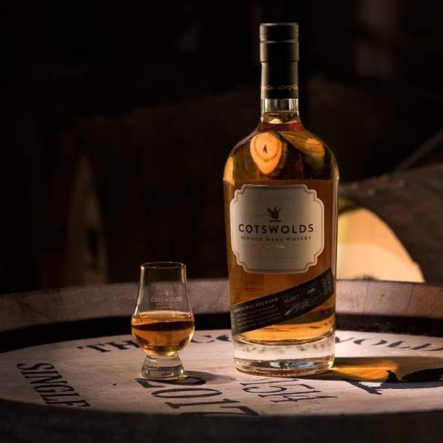 A glass and bottle of Cotswolds Single Malt Whisky on a whisky barrel