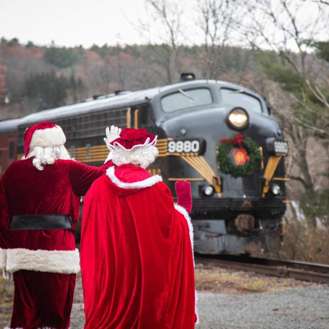 Santa and Mrs. Claus waving as train passes by