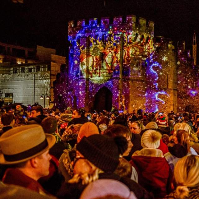 Crowd watching Christmas Market light projection show on bargate