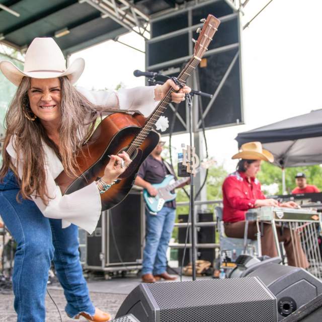 Female guitarist on stage, smiling at the camera