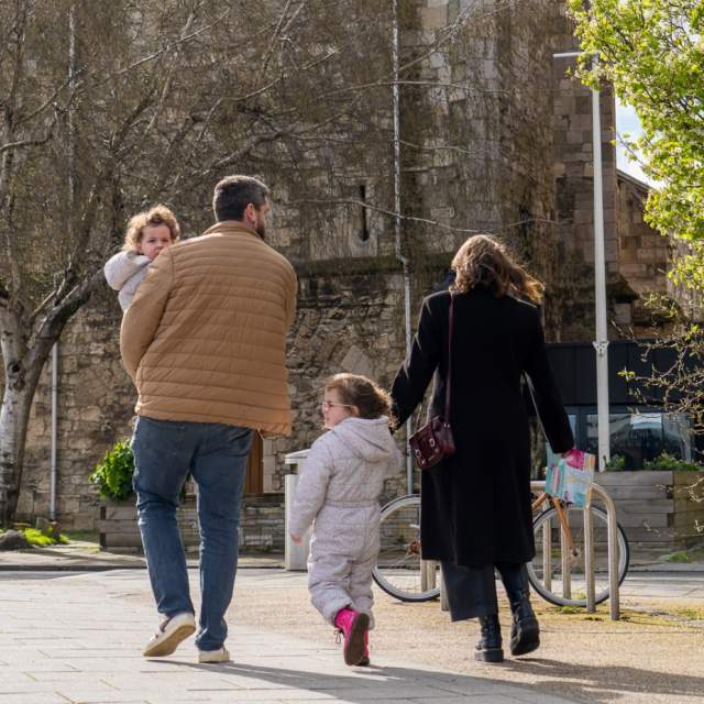 Young family walking on pavement with Easter trail maps in hand