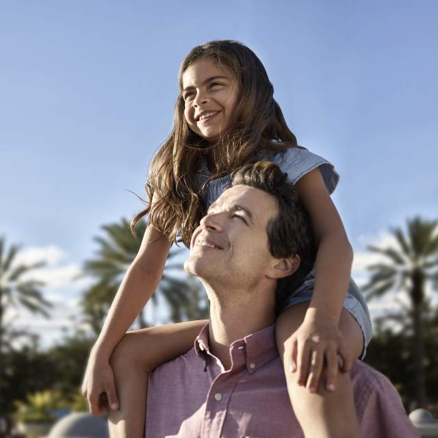 A girl on her father's shoulders smiling