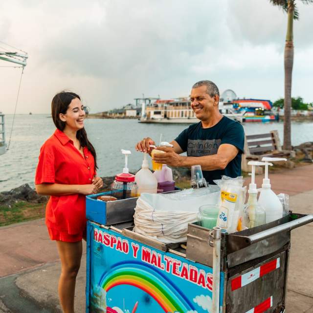Turista comprando un raspado a un vendedor ambulante en la Calzada de Amador, Ciudad de Panamá