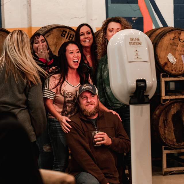 A group of people smiling at a selfie station at Braxton Brewing Co.