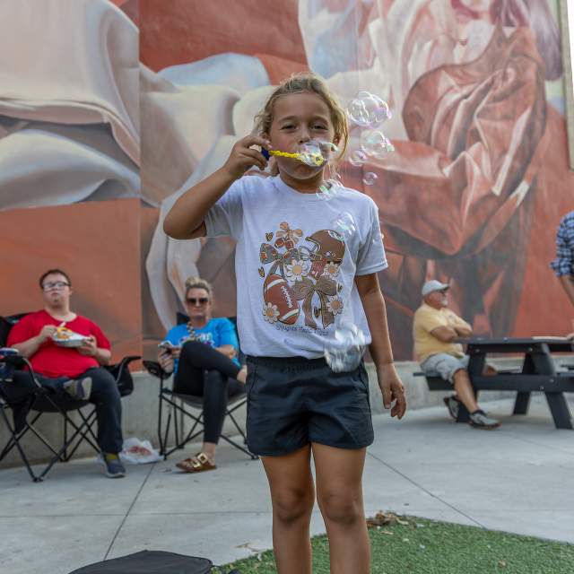 Kid blowing bubbles in front of mural