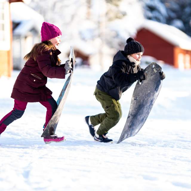 Two girls running with a toboggan to speed down the hill