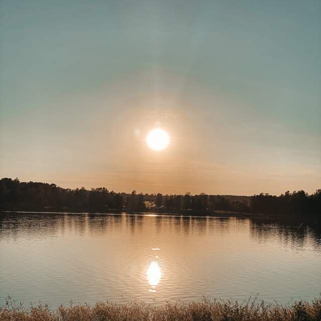 Solnedgang med refleksjon i vannet. Foto