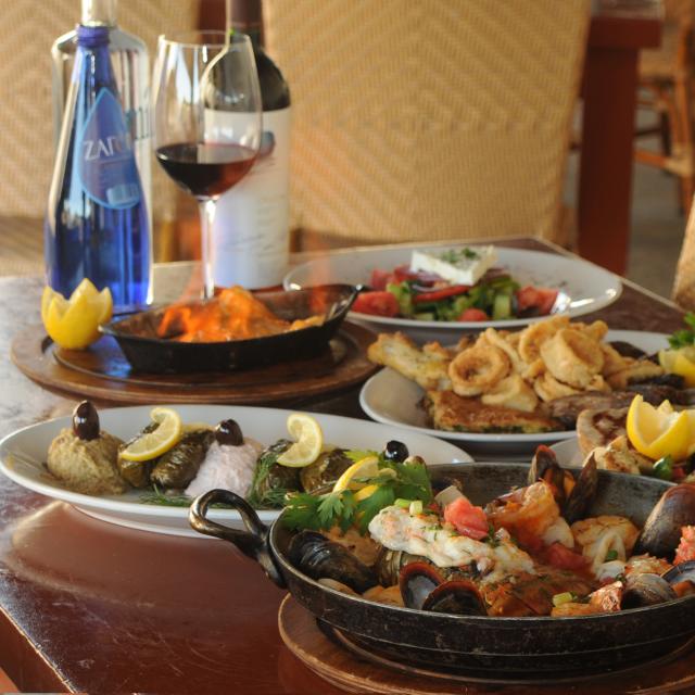 A table at Taverna Opa with a variety of food and wine