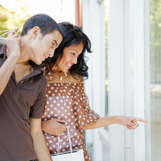 A hispanic couple window shopping.