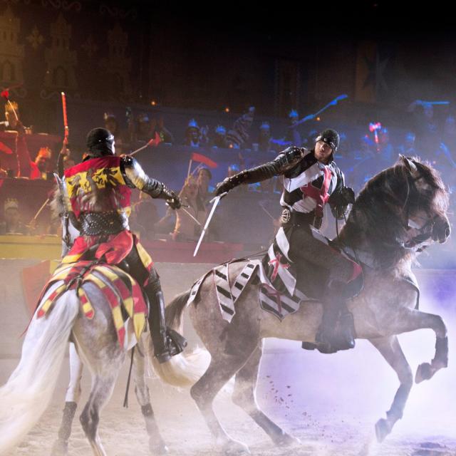 Two knights on horseback battle with swords at Medieval Times Dinner & Tournament