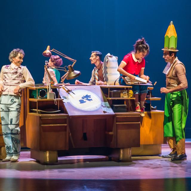 Performers gathered around an animation table in Cirque Du Soleil - Drawn to Life.